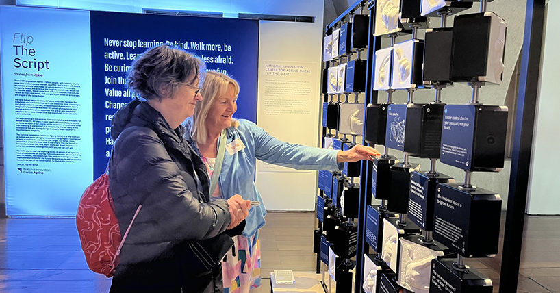 2 women looking at the exhibition which features plastercasts of hands